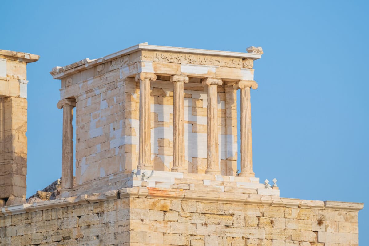 Ancient Greek Temple of Athena Nike on Athens Acropolis during summer with Ionic columns and mythological reliefs.