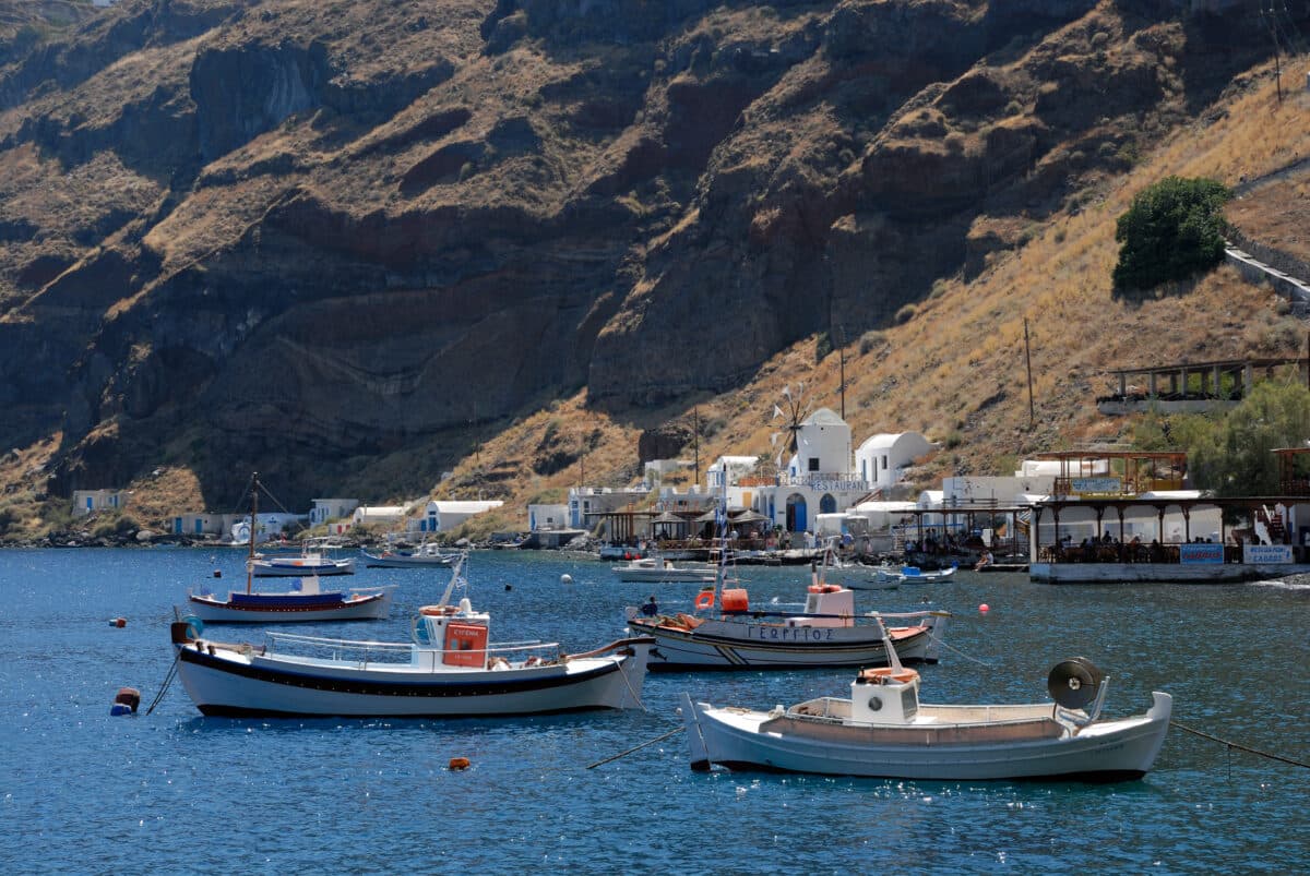 Charming Greek island Thirassia harbor with fishing boats, whitewashed buildings, and scenic Cycladic landscapes.