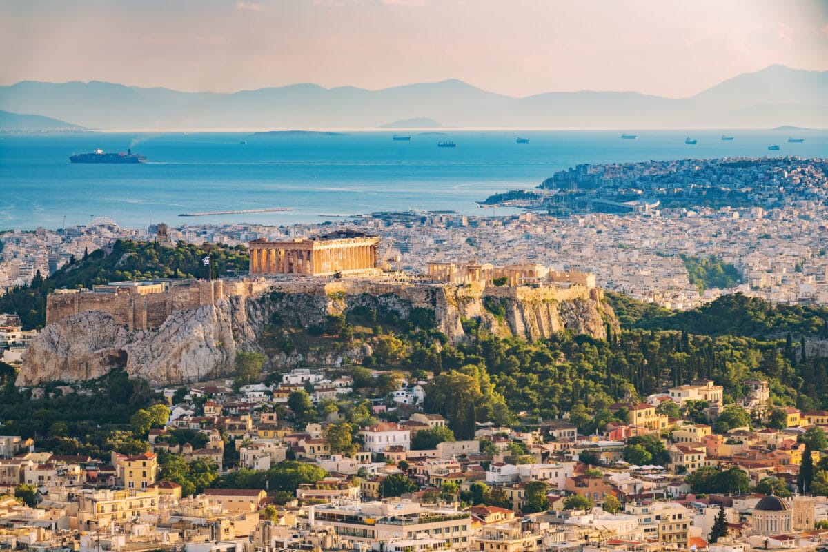 Aerial view of Athens with Acropolis, Parthenon, cityscape, sea, and mountains in summer.