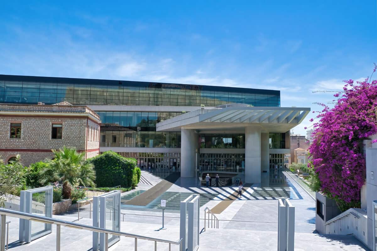 Modern Acropolis Museum in Athens with glass façade, greenery, and views of the Parthenon.