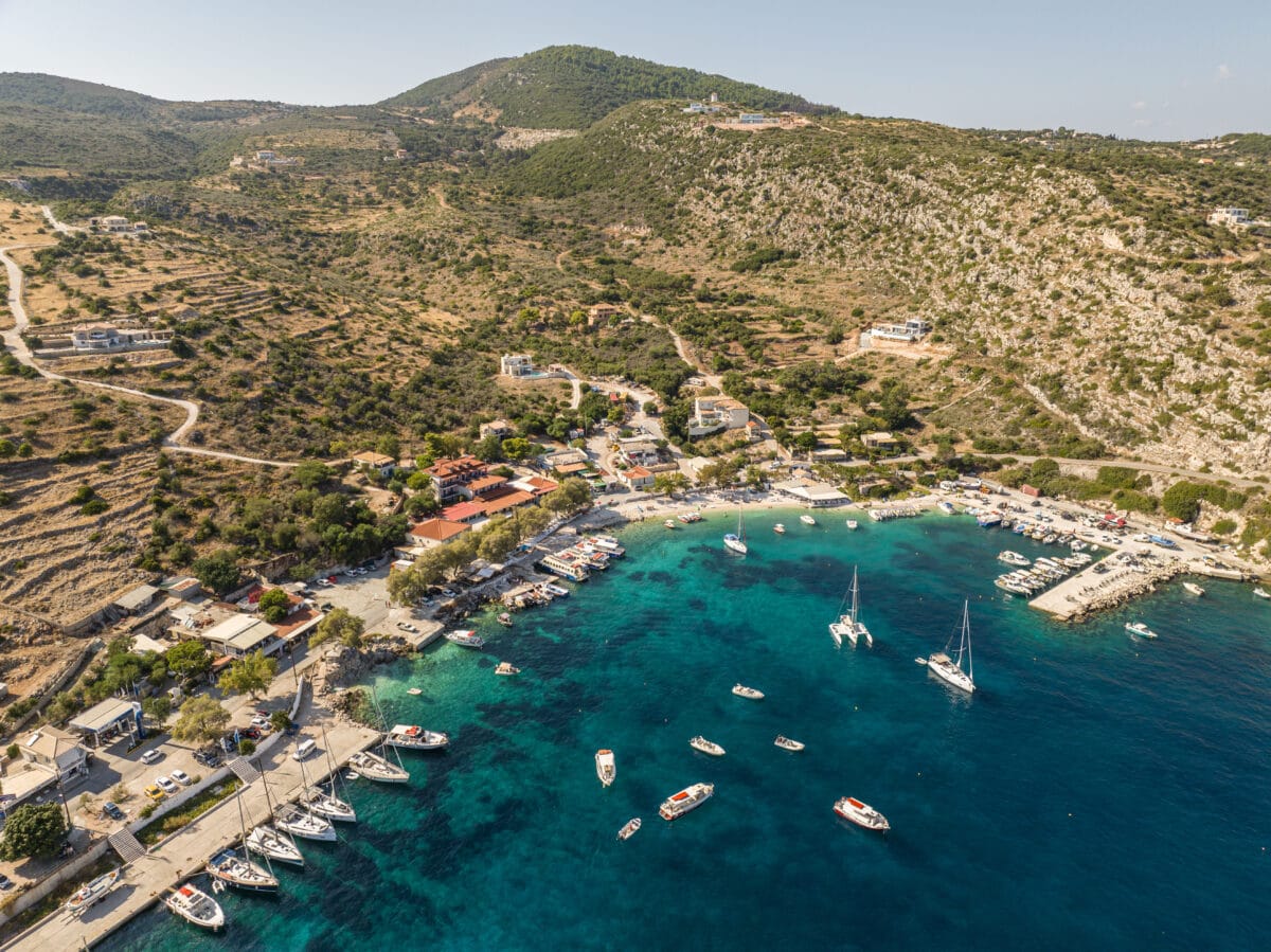 Aerial view of Agios Nikolaos port on Zakynthos Island with boats, turquoise waters, and Greek coastal scenery.