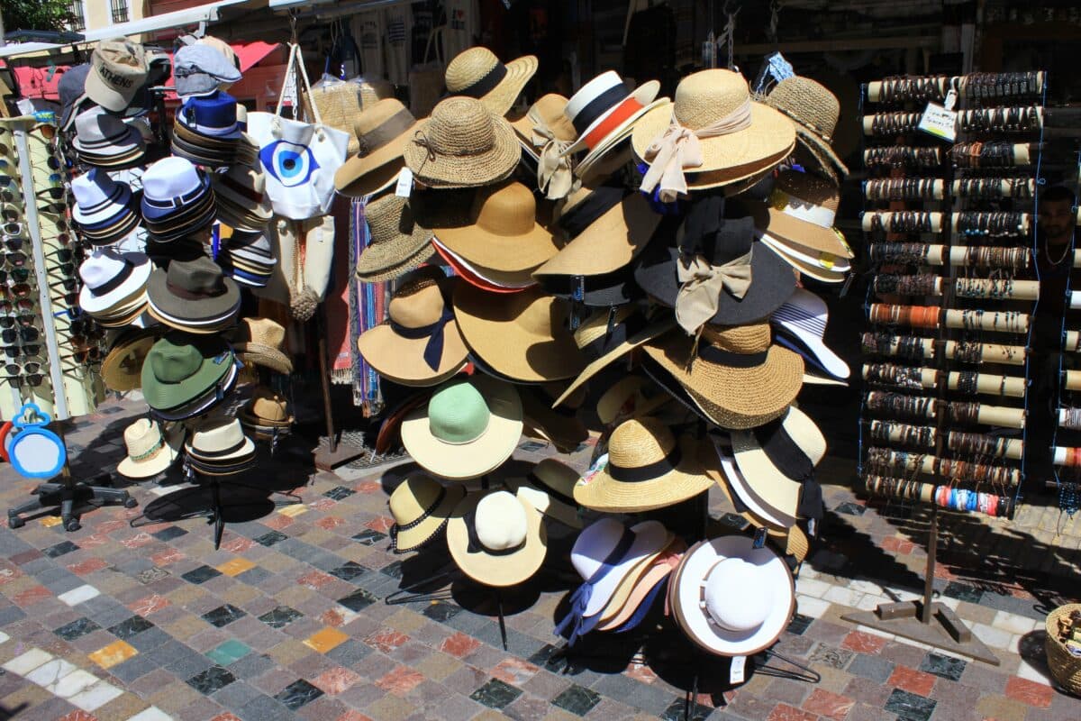 Colorful hats and souvenirs on display at Monastiraki square market in Athens, Greece.