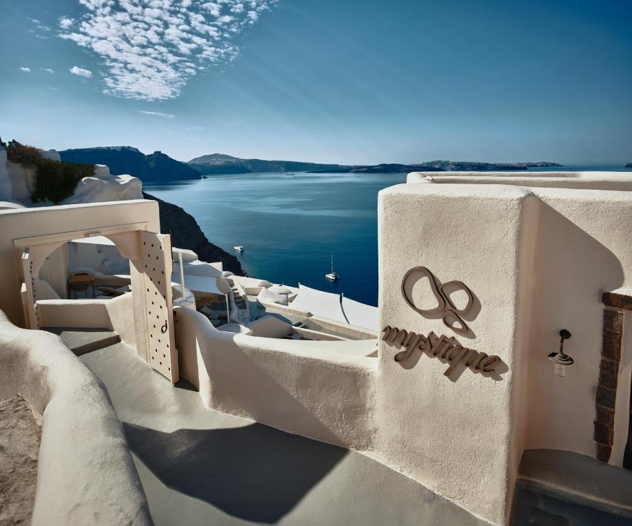 Mystique, a Luxury Collection Hotel with sea view, Whitewashed architecture, boats, and coastal landscape.