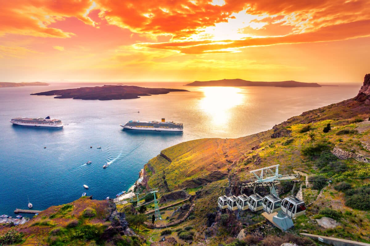 Breathtaking sunset over Fira, Santorini caldera, volcano, cruise ships, and scenic Aegean Sea.
