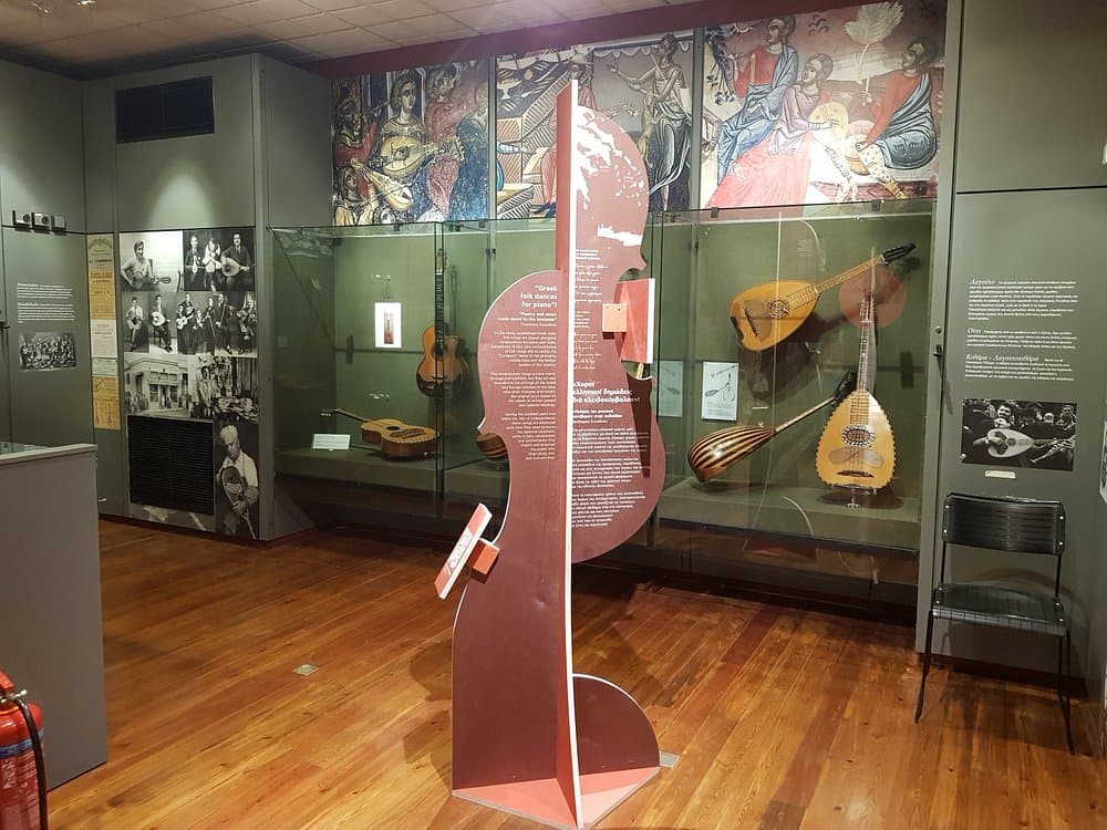 Exhibition of traditional Greek folk string instruments with glass displays and historical photographs in Museum of Greek Folk Musical Instruments