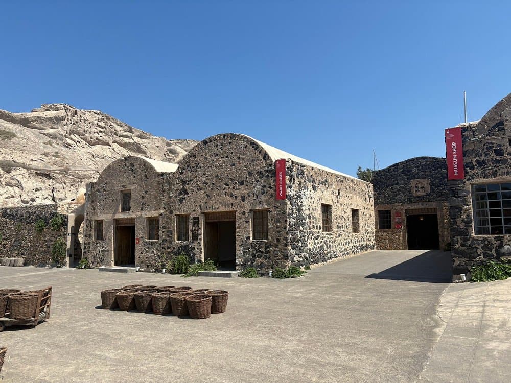 Historic stone Tomato Industrial Museum, D.Nomikos with wicker baskets, warehouses, museum shop, and volcanic rock buildings.