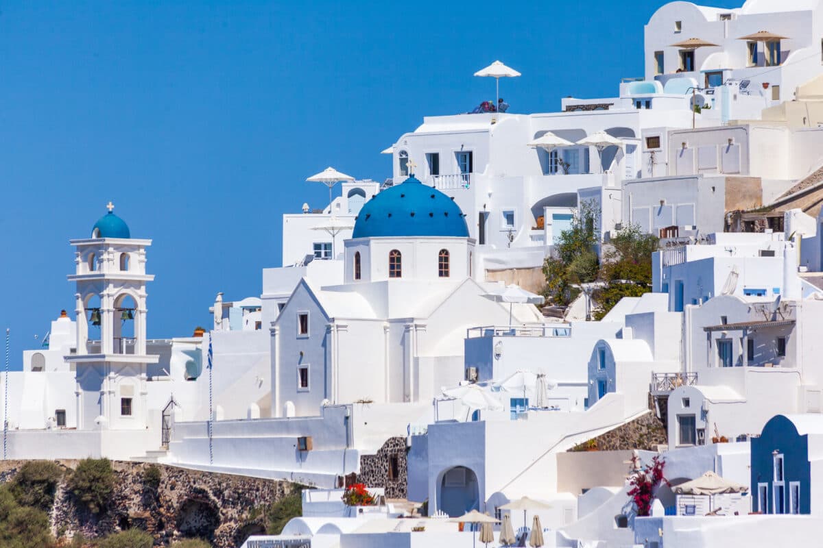 Scenic view of Imerovigli, Santorini with iconic blue-domed Anastasi church and white Cycladic architecture.