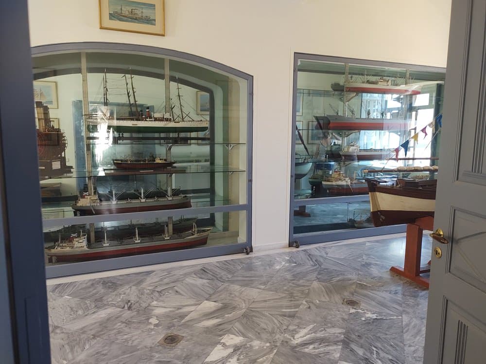 Naval Maritime Museum Oia Santorini with detailed ship models, nautical artwork, and glass display cases in an elegant exhibit room.
