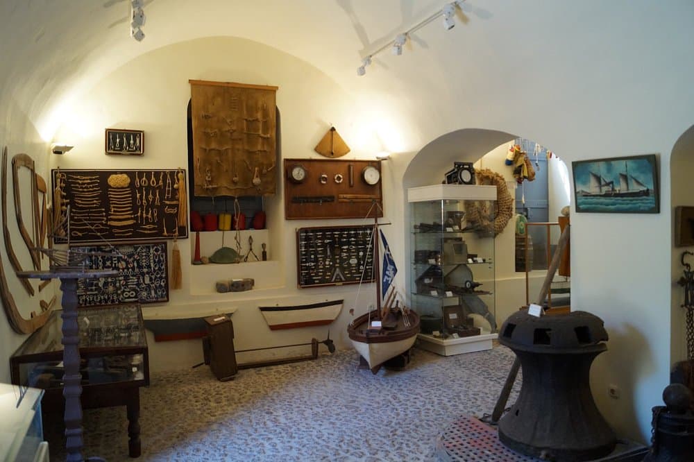 Santorini Maritime Museum interior showcasing nautical artifacts, models, ropes, ship paintings, and maritime history exhibits.