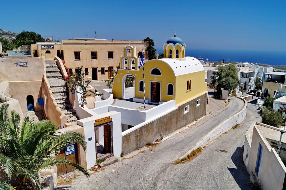 Lignos Folklore Museum Greece with pastel church, museum, Mediterranean architecture, and sea view.