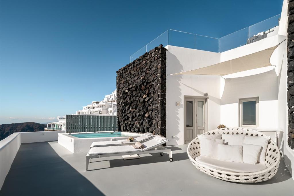 Grace Hotel Santorini outdoor terrace with pool, sun loungers, white architecture, and scenic hillside view.