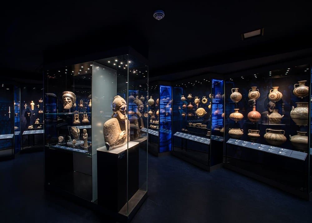 Ancient artifacts and pottery exhibit in Museum of Cycladic Art with sculptures and glass display cases.