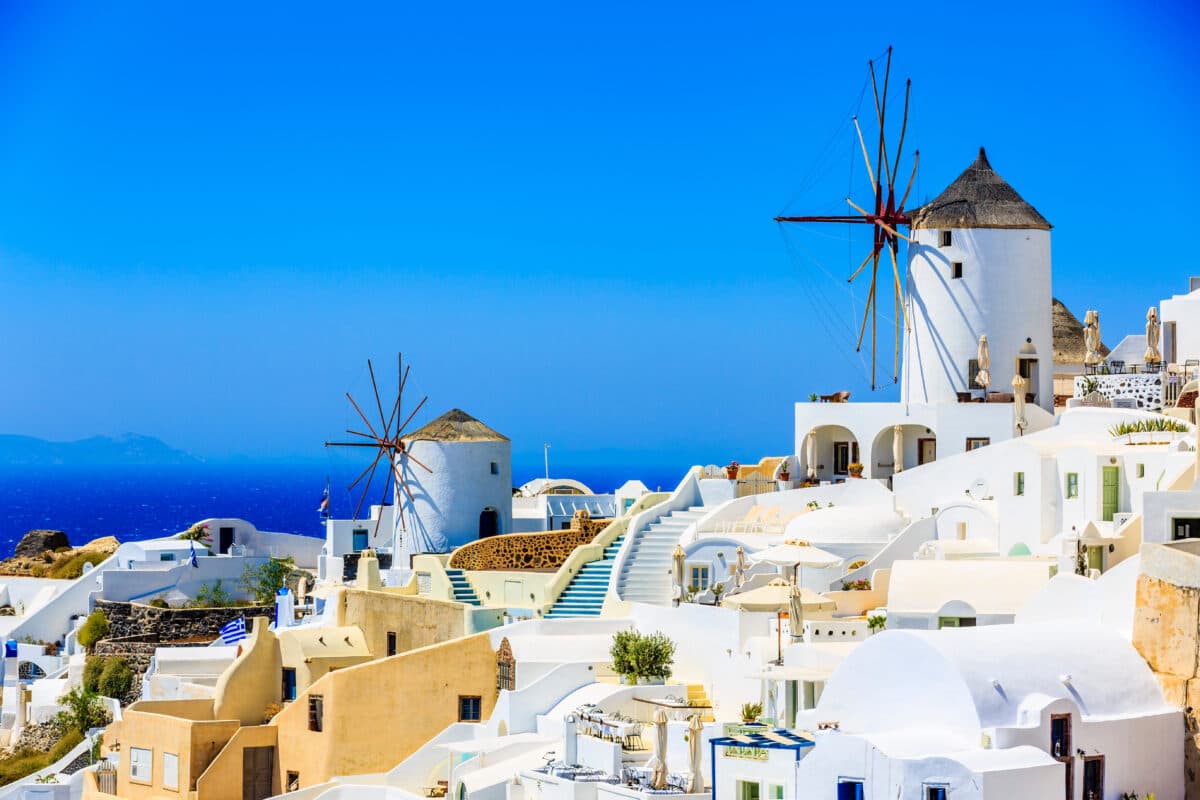 Santorini Oia windmills with whitewashed buildings and stunning Aegean Sea view.