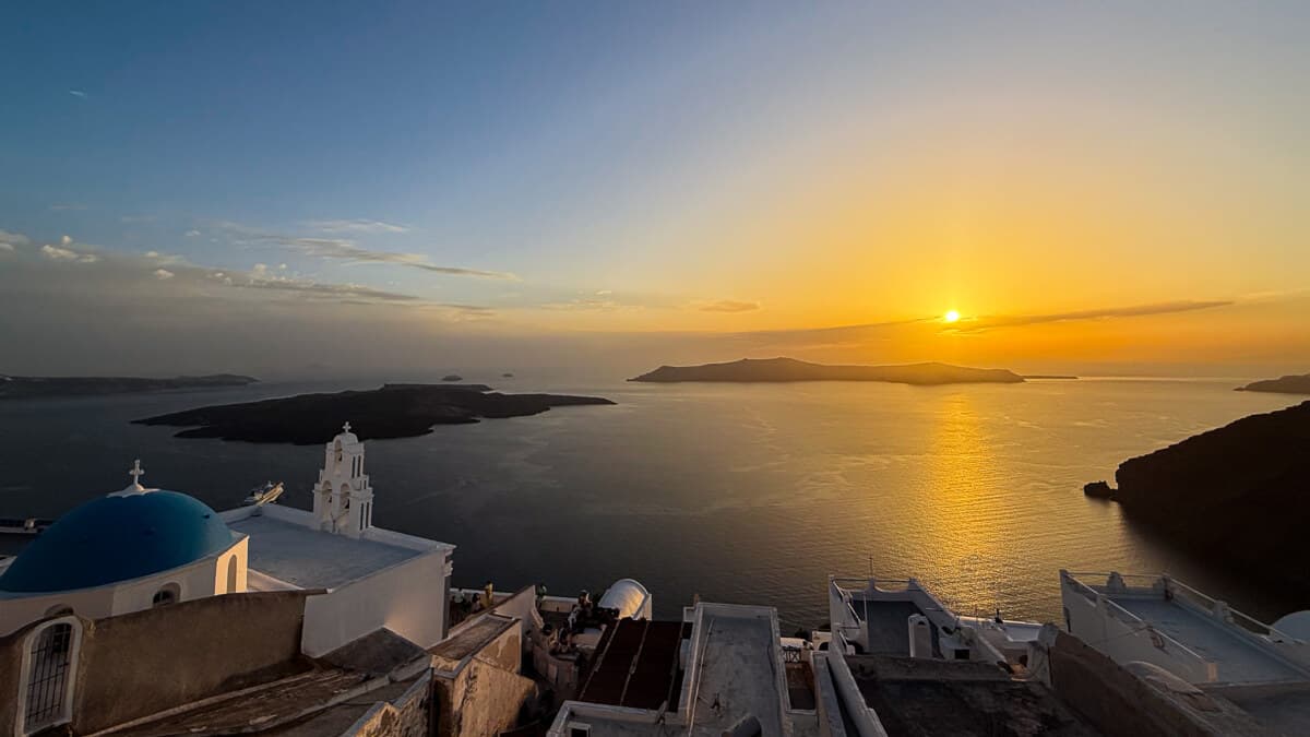 Panoramic view of Santorini's caldera with white-washed buildings and blue domes overlooking the Aegean Sea