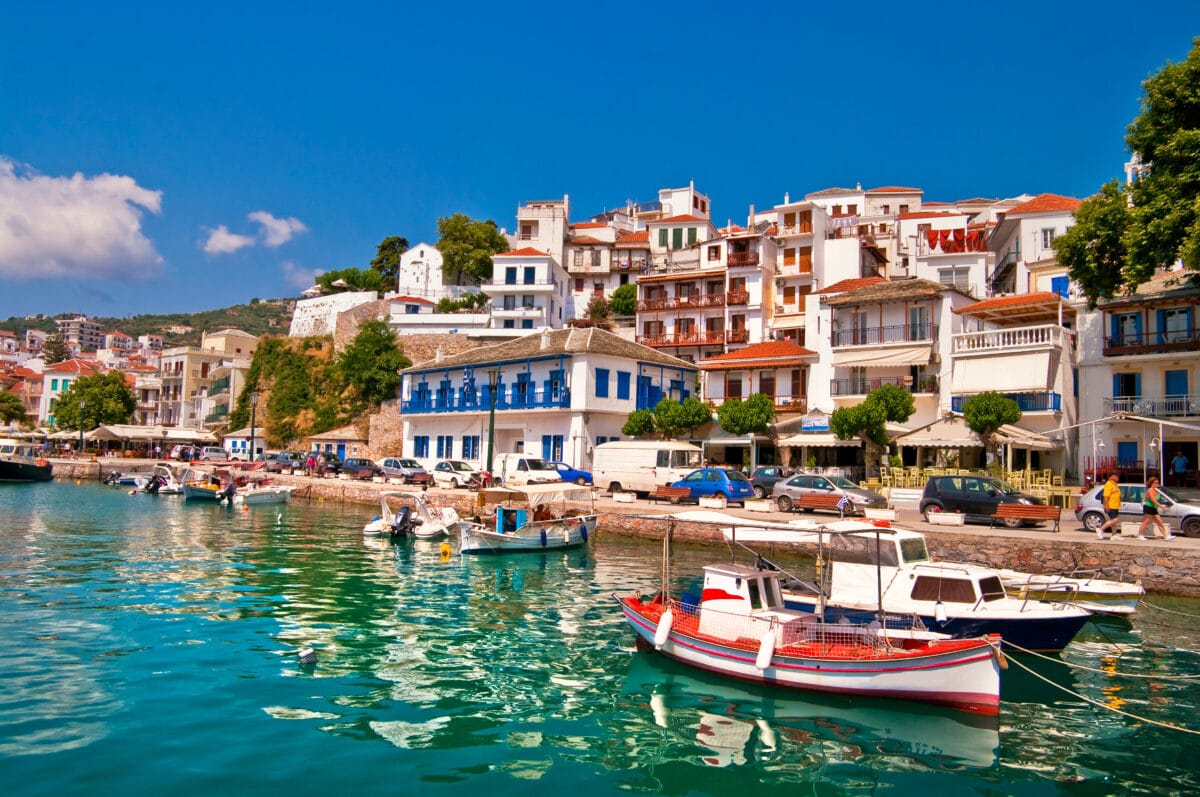 Beautiful Skiathos harbor with colorful boats, white Greek buildings, and scenic seaside village.